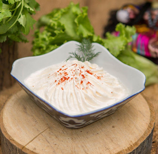 A bowl of yogurt sitting on top of a wooden stump