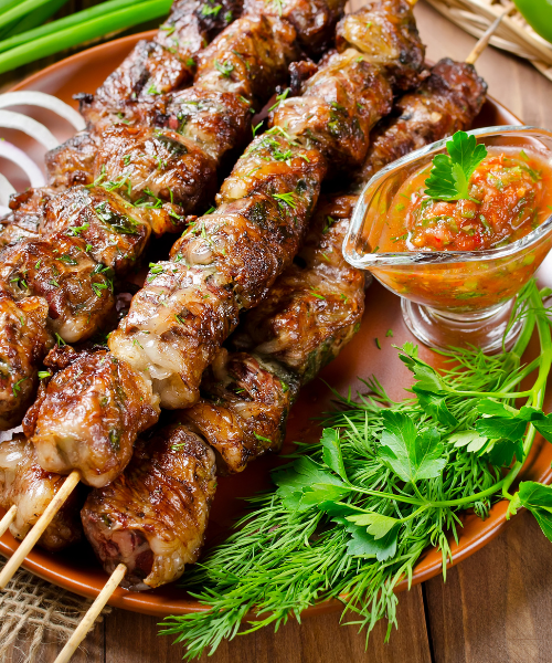 A plate of meat skewers with a dipping sauce